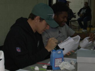 Eagles punter Braden Mann assists young boys in collecting money for their Africa trip.