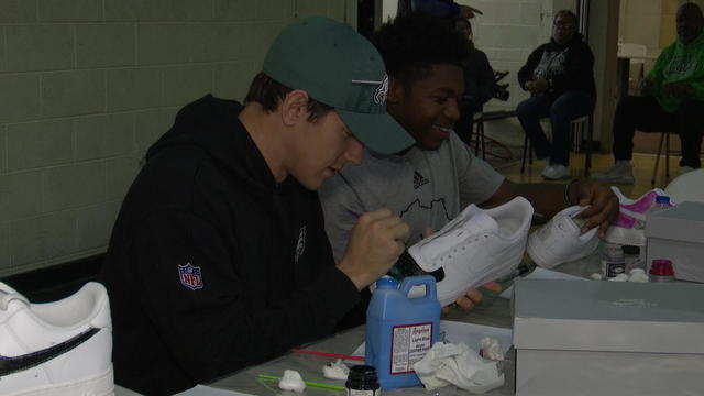 Eagles punter Braden Mann assists young boys in collecting money for their Africa trip.